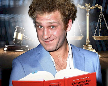 Ein Mann mit blauem Anzug liest ein rotes Gesetzbuch