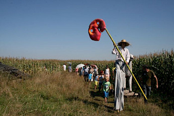 Ein Mann läuft auf einer Stange mit großem Plastikbrezel