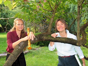 2 Frauen stehen hinter einem Glied eines Baum