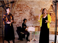 3 Frauen spielen Musik in Kirche: 1 singt, 1 spielt Flöte, 1 Cembalo