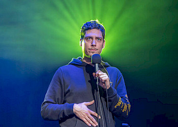 1 Mann im grünen Licht, er sieht ernsthaft aus und steht vor einer Mikrophone