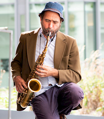 1 Mann spielt Saxophon. Er kniet
