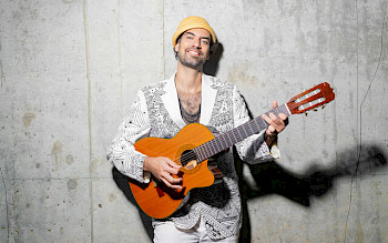 Ein Man mit gelbem Hut spielt Gitarre