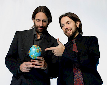 2 Männer mit Anzügen spielen einen kleinen Globus