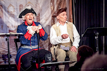 2 Männer mit Kostümem von 17. Jahrhundert sitzen nebeneinander