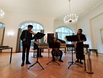 4 Musiker mit klassischen Instrumenten in einem schönen Saal