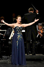 1 Frau mit blauem Kleid singt auf der Bühne