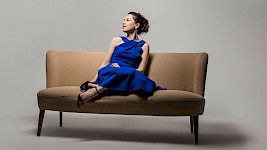 1 Frau mit blauem Kleid sitzt auf dem Sofa