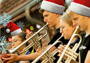 Kinder mit Weihnachtsmützen spielen Trompeten