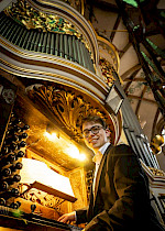 Ein Mann lächelt neben einem Orgel