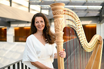 1 Frau steht neben einer Harfe