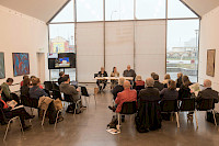 Pressekonferenz, Podium mit drei Personen, in einem hellen Raum