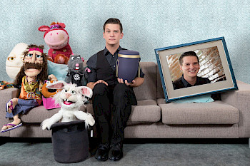 Tim Becker Bauchredner auf einem Sofa mit Puppen