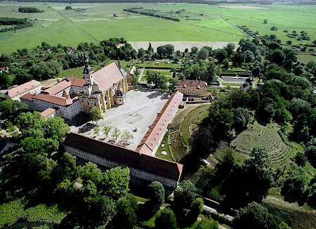 Altes Kloster-Gelände von oben fotografiert, mit einer grünen Fläche mit Wiesen und Bäumen drumherum an einem sonnigen Tag